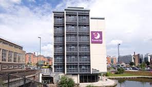 A multi-story Premier Inn hotel building with large windows, located near a waterway in an urban area, just a short walk from Nottingham Arena.